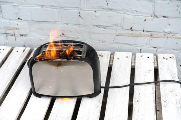 Yanan tost makinesi. Tost iki dilim tost beyaz arka plan üzerinde alev aldı. Elektrikli aletlerin dikkatsiz cerenliği tehlikesi. Yangın