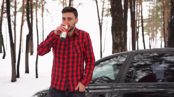 Привлекательный кавказский мужчина стоит в зимнем лесу возле своей машины . — стоковое видео