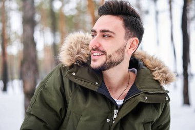 Kış mevsimi ormanlarında dışarıda duran yakışıklı, sakallı, beyaz bir adam. Çekici stil Avrupalı bağırsağı karlı Noel ormanlarında yürüyor. Tatil sezonu tatili                       