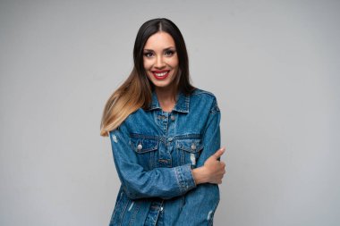 Beyaz arka planda stüdyoda poz veren güzel beyaz kadın kot ceketi. Şirin esmer. Denim tarzı kırmızı dudaklar zarif makyaj. İçeride duran genç bir kadın hayranlık uyandırdı.