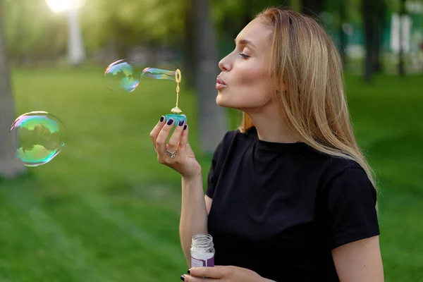 夏の晴れた公園で石鹸泡を吹いて若い美しい女の子夏のレジャー ポジティブで幸せな人々 — ストック写真