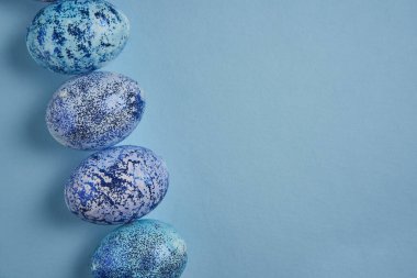 Beautiful blue easter eggs lie in a row on a blue paper background. Easter background. Seasonal holiday flat lay with free space for text. Classic blue color of the year 2020