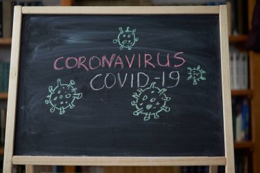 Salgın Uyarısı. Dünya çapındaki koronavirüs salgınıyla ilgili olarak tahtaya beyaz tebeşir yazılmış. Siyah zemin üzerine Covid 19 pandemik metin ve boş alan. çizilmiş virüs bakterisi