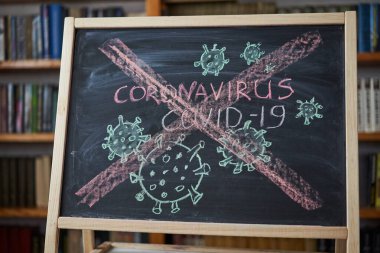 Salgın Uyarısı. Dünya çapındaki koronavirüs salgınıyla ilgili olarak tahtaya beyaz tebeşir yazılmış. Siyah zemin üzerine Covid 19 pandemik metin ve boş alan. çizilmiş virüs bakterisi