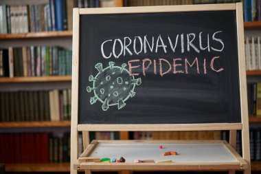 Salgın Uyarısı. Dünya çapındaki koronavirüs salgınıyla ilgili olarak tahtaya beyaz tebeşir yazılmış. Siyah zemin üzerine Covid 19 pandemik metin ve boş alan. çizilmiş virüs bakterisi