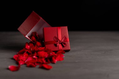 Koyu bir çimento arka plan üzerinde bir hediye kırmızı kutu yanında güzel kırmızı güller. Yeni Yıl Noel doğum günü Sevgililer Günü Anneler Günü hediyesi