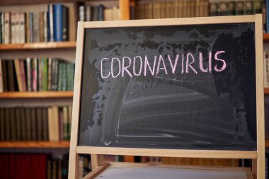Salgın Uyarısı. Dünya çapındaki koronavirüs salgınıyla ilgili olarak tahtaya beyaz tebeşir yazılmış. Siyah arkaplan ve boş alan üzerine Covid 19 pandemik metin.