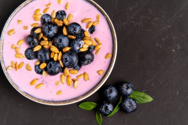 Lezzetli taze yaban mersinli yoğurt, siyah masa arkasında duran seramik kasede sallanan tatlı. Ev yapımı böğürtlen suyu. Sağlıklı beslenme. Diyet yemek. yoğurt