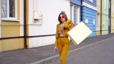 Bir genç Avrupalı Avrupalı kız sokakta paketler içinde alışverişlerle yürüyor.. 
