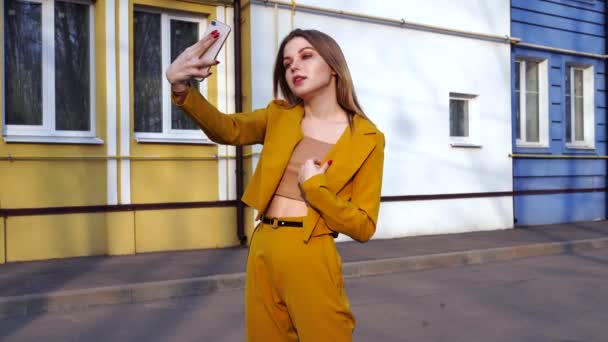 Bella giovane ragazza caucasica 20 anni con i capelli bianchi vestiti elegante abito arancione fa selfie al telefono mentre in piedi sulla strada . — Video Stock