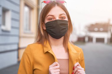 20 yaşında, siyah koruyucu maske takan, salgın Coronavirus Covid-19 adlı genç Avrupalı bir kız. Şık tıbbi maskeli bir kadın, insanları karantinaya alıyor.