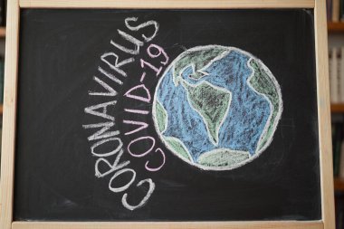 Dünya Gezegeni Salgın Uyarısı Tehlike altında. Dünya çapındaki koronavirüs salgınıyla ilgili olarak tahtaya beyaz tebeşir yazılmış. Siyah arkaplan üzerine Covid 19 pandemik metin 