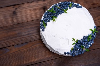 İştah açıcı cheesecake bisküvi yastığı süslemeli beyaz krema yaban mersini ve nane şekerleri ahşap kırsal masada duruyor. Tabağında parça olan tatlı pasta. 