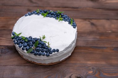 İştah açıcı cheesecake bisküvi yastığı süslemeli beyaz krema yaban mersini ve nane şekerleri ahşap kırsal masada duruyor. Tabağında parça olan tatlı pasta. 