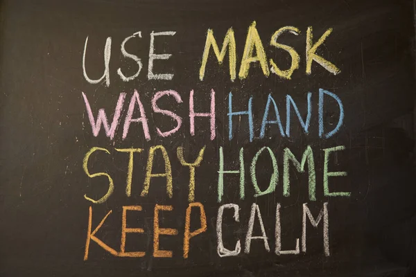 Use mask wash your hand Stay home Outbreak Warning. written white chalk on blackboard in connection with epidemic of coronavirus worldwide. Covid 19 pandemic Text on black background with free space.