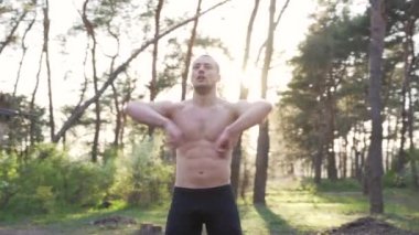 Yakışıklı erkekler sabah antrenmanı için dışarıda antreman yapıyor. Spor sahasında doğa ormanı dışında egzersiz yapmadan önce kolunu esnet.