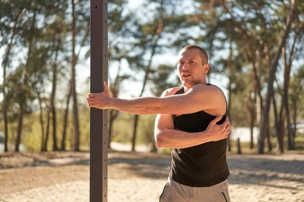 Handsome caucasian men outdoor workout cross training morning workout. Stretching arm before exercising outside sports ground nature forest Healthy lifestyle Young adult male fit body on fresh air