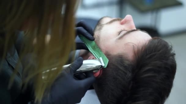 在现代理发店里，年轻美丽的高加索女人理发师剪胡子英俊男子 — 图库视频影像