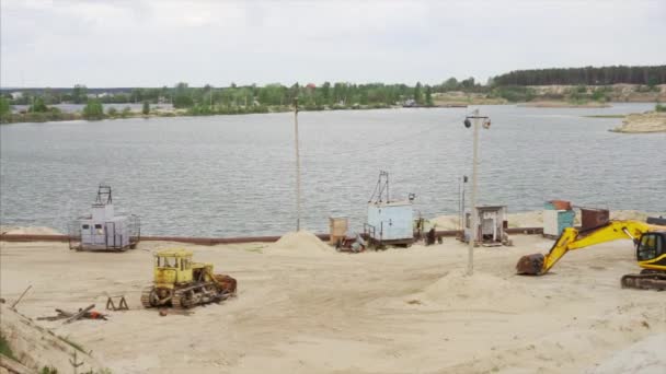 Areia pedreira indústria de mineração equipamento escavadeira trator terra areia pé perto de água do lago — Vídeo de Stock