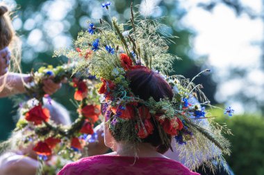 Tarla çiçeklerinin, otların ve tahılların yaz gündönümü çelengi; taç dokuma süreci ve kafaya uyma