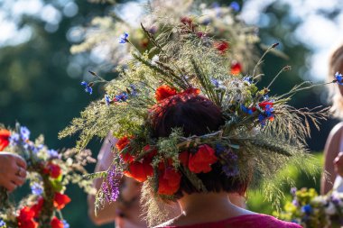 Tarla çiçeklerinin, otların ve tahılların yaz gündönümü çelengi; taç dokuma süreci ve kafaya uyma