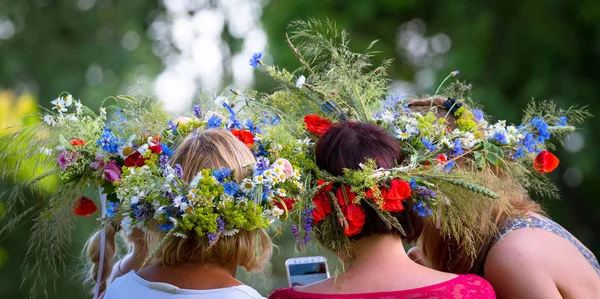 view of girls from behind, summer solstice wreaths on flowers on heads, pictures on phone