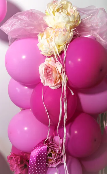 pembe ve kırmızı balonlar birbirine bağlanmış ve çiçek süslemeleri ve kurdelelerle süslenmiş.