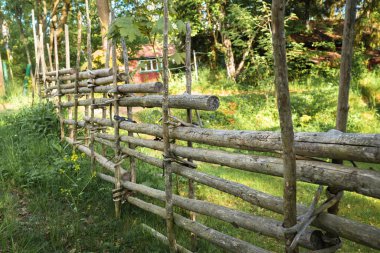 Doğal ahşap tahtalardan yapılmış eski bahçe çiti, tüm bağlar çiviler olmadan, sadece ağaç kabuğu ile; keskinlik sadece ortasında