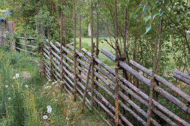 Çivisi olmayan doğal tahta kazıklardan yapılmış eski bahçe çiti. Eski efekt.