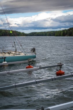 Kırmızı şamandıralarda demir atan kayıklar. Yaz günü, karşı kıyıdaki orman.