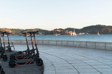 Lizbon, Portekiz, 27.09.2019: nehir manzaralı etiketler ve yatlar, ön planda elektrikli scooterlar, kıyıda dağlar