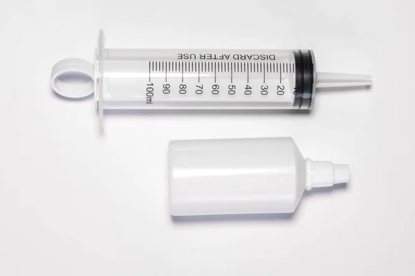 Beyaz arka planda yeni, boş, büyük 100 ml plastik şırınga ve şişe