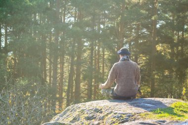 Kazaklı bir adam kayanın üzerinde meditasyon yapıyor..