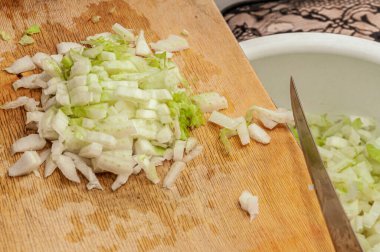 İyi doğranmış Çin lahanası. Plastik bir kasede tahta bir tahtadan tırmıklanmış.