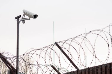 Dikenli tellerin üzerinden güvenlik kamerası. Kamera görüntülerine odaklan.