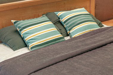 Yatağın başlığı. Çizgili yastıklı düzgünce yerleştirilmiş yatak.