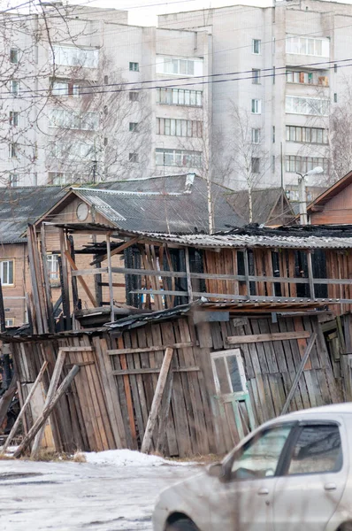 sad cityscape with a collapsed shed, wooden house and apartment building