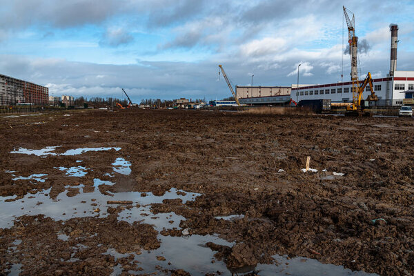 Saint Petersburg, Russia - 11 February 2020. landscape with a dirty field, cranes and blue sky. long exposure