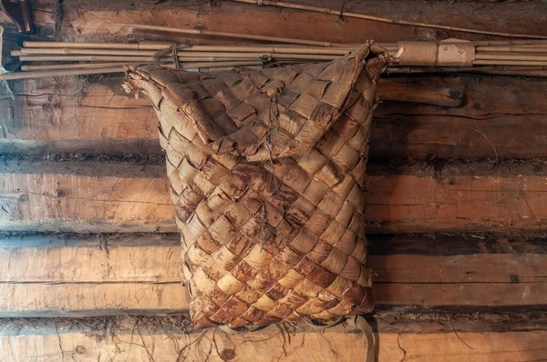 一个用桦树树皮制成的旧的肩篮放在一座圆木村舍的墙上 俄罗斯族家庭物品 — 图库照片