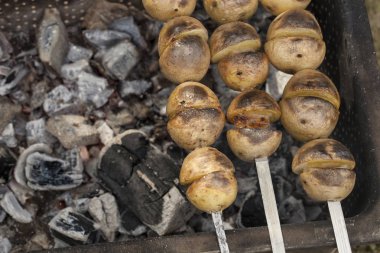 Izgara kömürün üzerindeki şampuanların üzerinde patates.