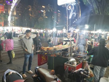 Dalat, Vietnam - December 12, 2019 Scene of crowded busy night marketplace with street vendor selling produce and wares on the sidewalk at Central Dalat Night 