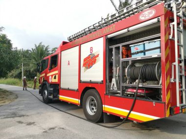 Perak,Malaysia. March 13,2020: Firemen extinguishing the fire with strong water hose at oil palm plantation along the Taman Bunga Raya Area.