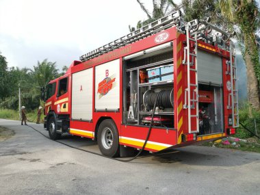 Perak,Malaysia. March 13,2020: Firemen extinguishing the fire with strong water hose at oil palm plantation along the Taman Bunga Raya Area.