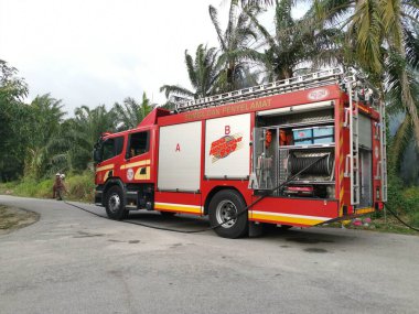 Perak,Malaysia. March 13,2020: Firemen extinguishing the fire with strong water hose at oil palm plantation along the Taman Bunga Raya Area.