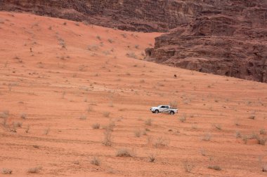 Araba, Wadi Rum çölünün kayalık dağlarının ortasında kumlu bir yamaçta ilerliyor. Mars cansız bir kırmızı manzaradır. Mart 2020 'de Ürdün' de çekildi.