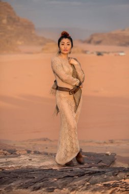 Şeffaf uzun elbiseli bir kız cansız Wadi Rum çölünün arka planında bir kayanın üzerinde duruyor. Ürdün 'de vuruldu..