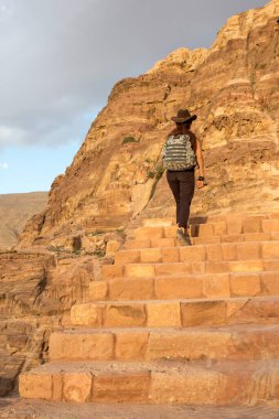 Sırt çantalı ve kovboy şapkalı bir turist dağlardaki antik taş merdivenlerden tırmanıyor..