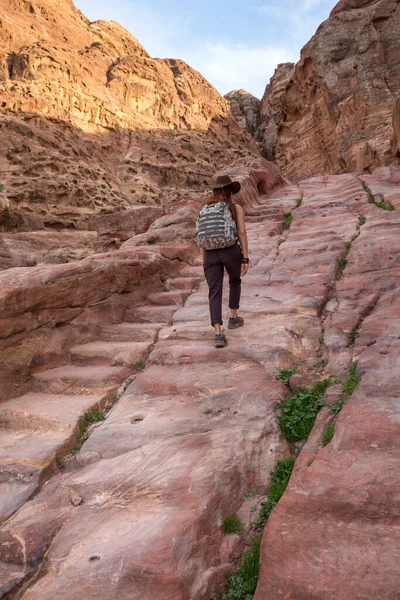 提着背包 头戴牛仔帽的女游客爬上用石头雕刻的古老石阶 — 图库照片