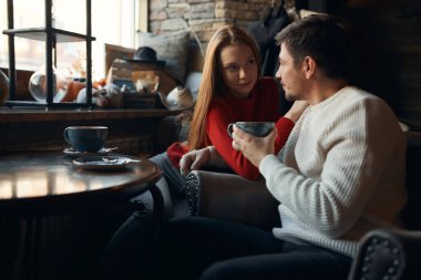 Genç ve harika bir bayan kollarını erkek arkadaşının omzuna koyuyor ve onun iltifatlarını dinliyor.