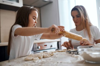 Küçük çocuk, annesi onu kontrol ederken merdaneyle çalışmayı öğreniyor.